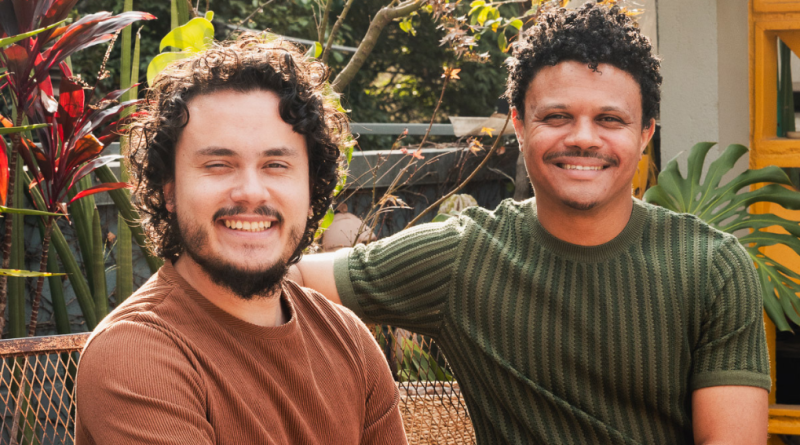 Antony Ventura e Ricardo Santiago, integrantes do Duo Inhambu, posam sorridentes em ambiente natural, cercados por plantas, simbolizando a leveza e a essência do novo single “Luz da Manhã”.