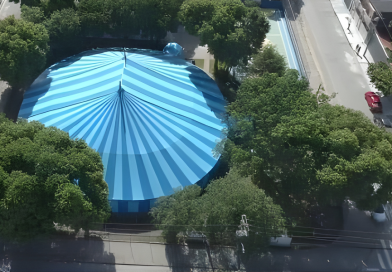 Vista aérea do Circo-Escola Cidade Seródio, com sua lona azul cercada por árvores, em Guarulhos.